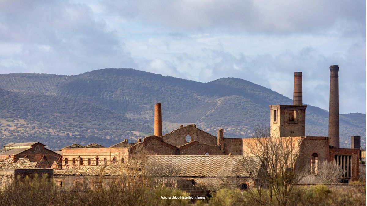 Verweerde fabriekshallen en hoge schoorstenen van de voormalige mijnindustrie in Peñarroya-Pueblonuevo, met de bergen van de Sierra Morena op de achtergrond – industrieel erfgoed in Andalusië