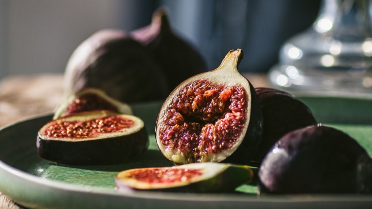 Close-up van rijpe vijgen op een groen bord, sfeervol gefotografeerd op een houten tafel – introbeeld voor vijgensalade met geitenkaas en honing bij Cortijo La Vista