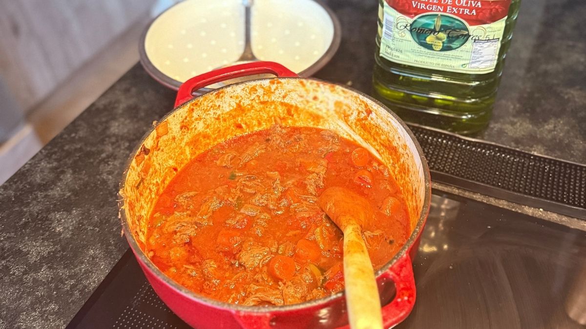 Rabo de toro, het Andalusische stoofgerecht, in een rode gietijzeren pan met groenten en rijke saus tijdens het sudderen bij Cortijo La Vista
