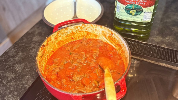 Rabo de toro, het Andalusische stoofgerecht, in een rode gietijzeren pan met groenten en rijke saus tijdens het sudderen bij Cortijo La Vista