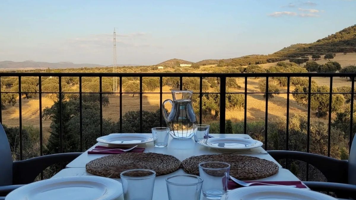 Gedekte eettafel op terras met uitzicht over heuvels en olijfbomen bij Cortijo La Vista in Andalusië.
